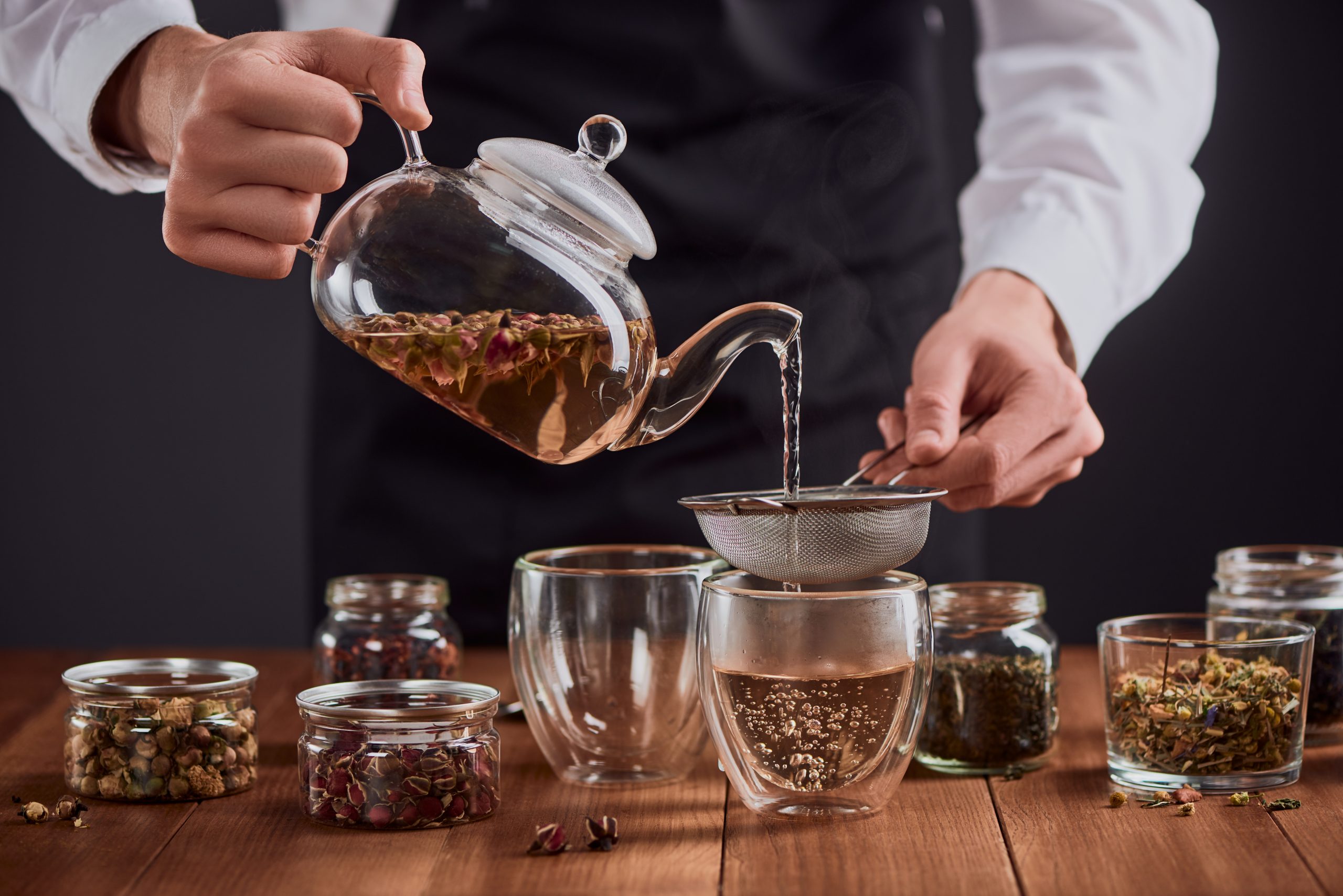 Tea,Master,Pouring,Green,Tea,With,Rose,Buds,Into,Glass